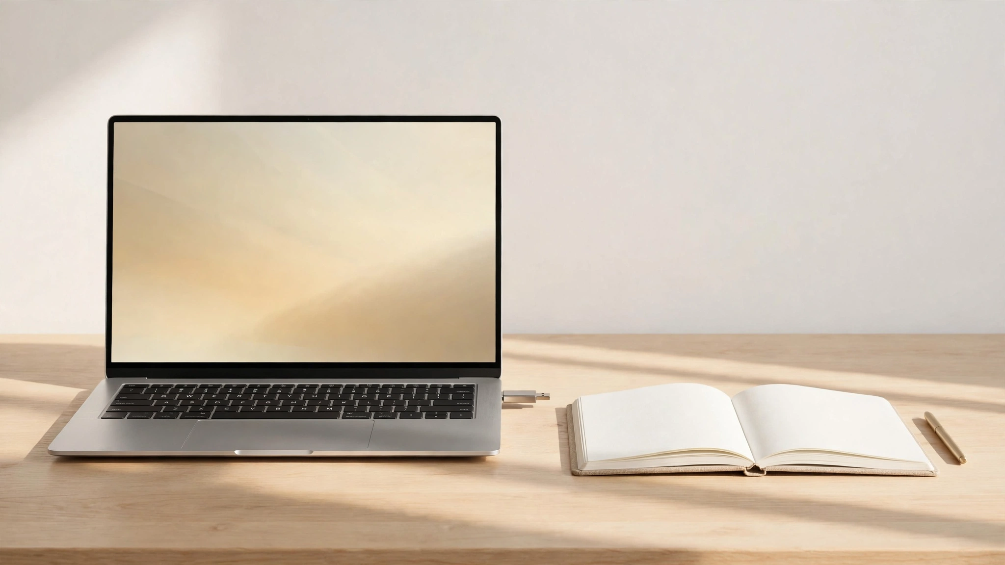 An installation workspace in morning light: a laptop with a USB drive plugged in, next to a blank notebook